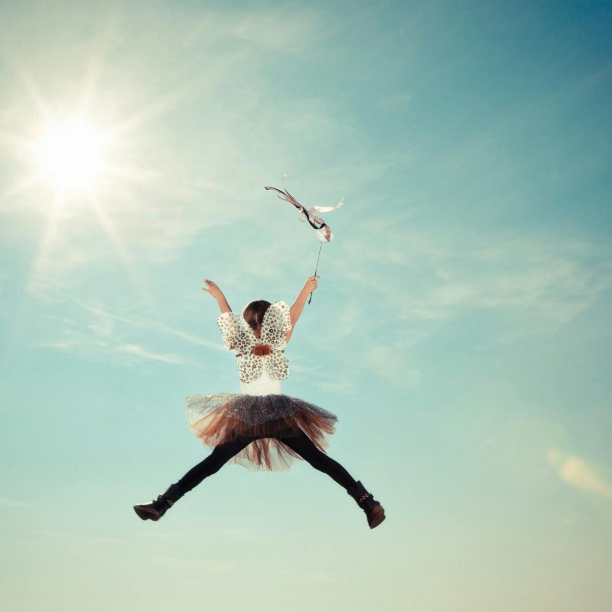 a-young-girl-joyfully-leaps-in-a-fairy-costume-under-the-bright-sun-capturing-a-moment-of-freedom-and-whimsy